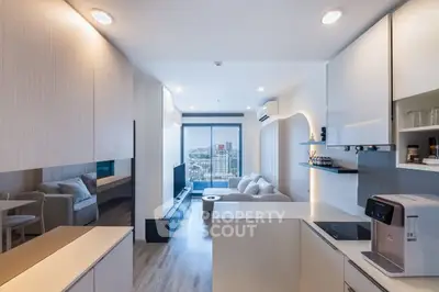 Modern open-layout living room with kitchen, featuring sleek design and city view.