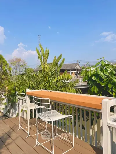 Charming outdoor balcony with lush greenery and seating, perfect for relaxation and enjoying nature views.