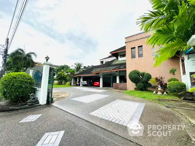 Spacious driveway leading to a modern house with lush greenery and carport.