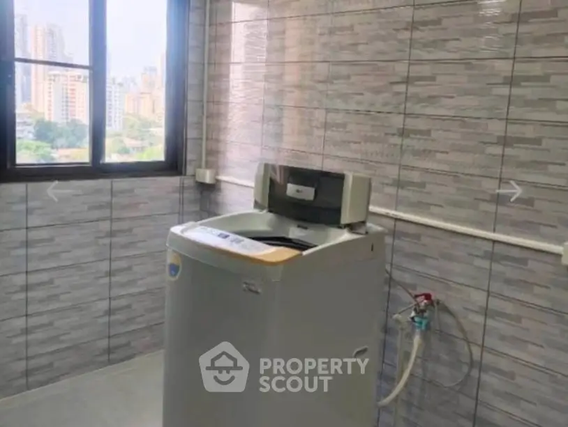 Spacious laundry room with modern washing machine and city view.