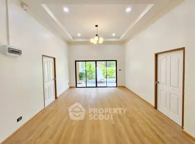 Spacious living room with elegant lighting and large windows overlooking a garden.