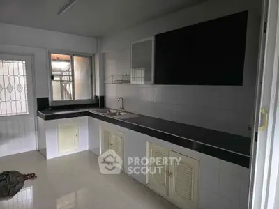Spacious kitchen with sleek black countertops and ample cabinet storage in modern home.
