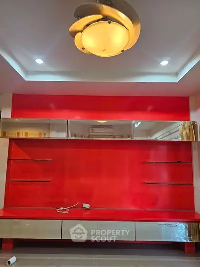 Modern living room with vibrant red accent wall and sleek built-in shelving.