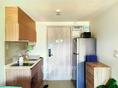 Modern compact kitchen with wooden cabinets and stainless steel appliances in a cozy apartment.