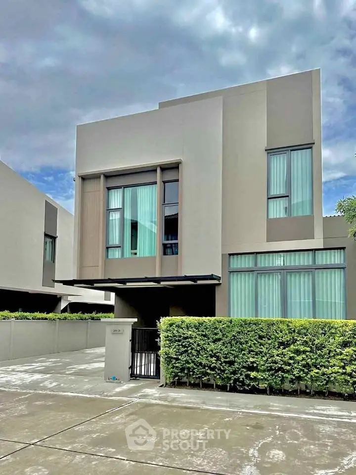 Modern two-story house with sleek design and large windows in a suburban neighborhood.