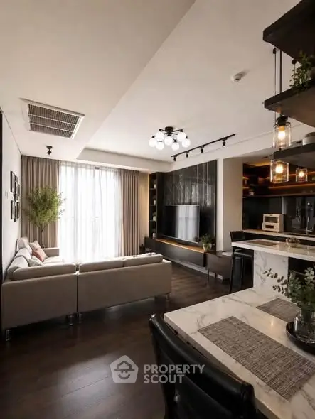 Modern living room with open kitchen, stylish decor, and natural light.