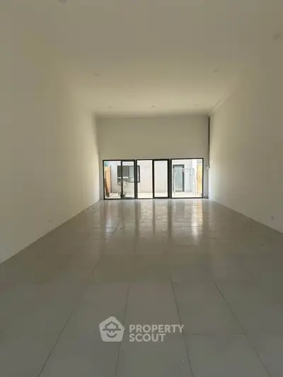 Spacious empty room with large windows and tiled flooring, ideal for customization.