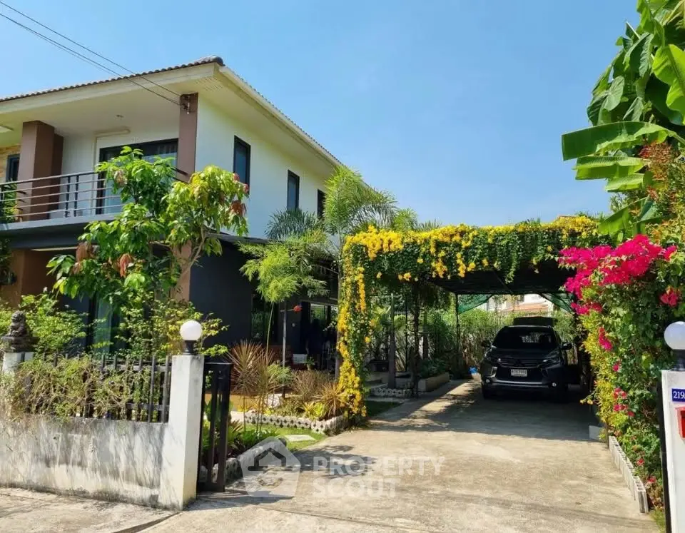 Charming two-story house with lush garden and covered driveway in a serene neighborhood.