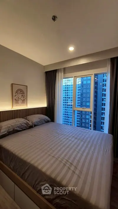 Modern bedroom with city view, featuring cozy bed and stylish decor in high-rise apartment.