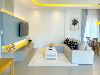 Modern living room with stylish decor and open dining area, featuring a cozy sectional sofa and wall-mounted TV.