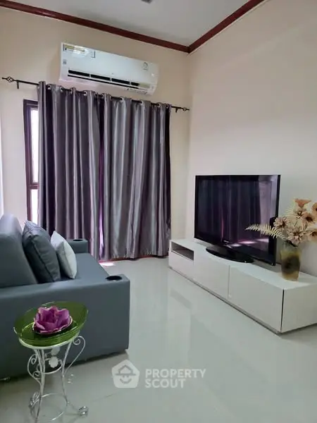 Modern living room with sleek furniture and large TV, featuring elegant curtains and air conditioning.