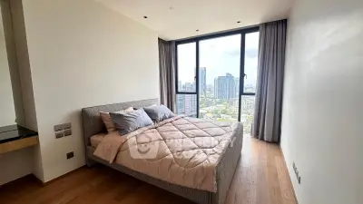 Modern bedroom with large windows offering stunning city views in a high-rise apartment.