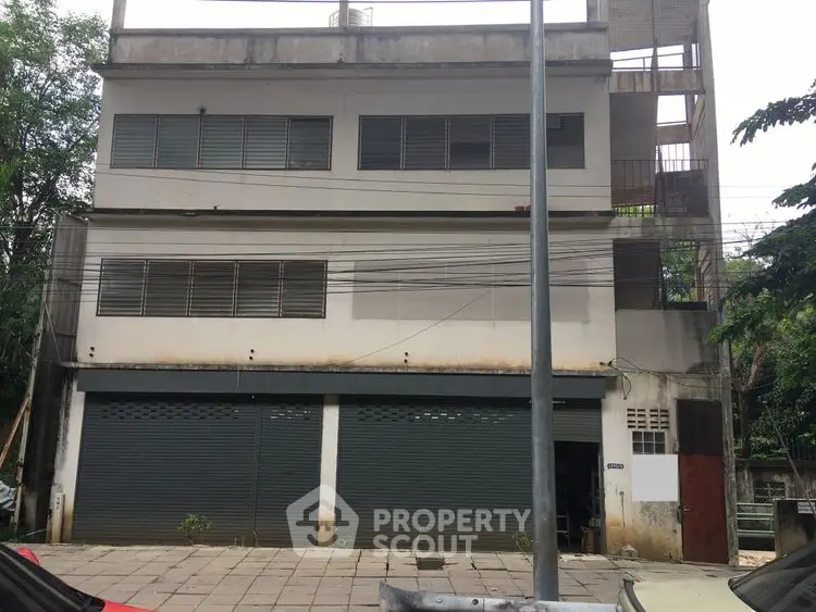 Three-story commercial building with shuttered storefronts and barred windows, ideal for business opportunities.