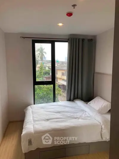 Cozy bedroom with large window and modern decor in urban apartment.