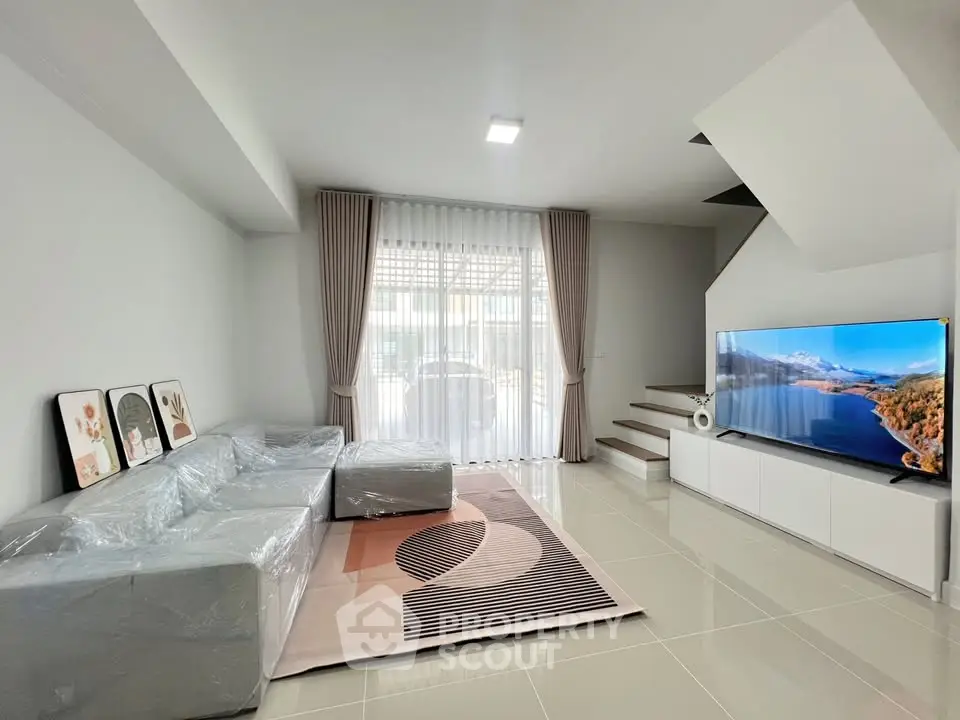 Spacious modern living room with sleek design and large TV, perfect for relaxation and entertainment.