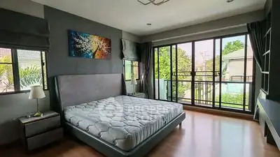 Spacious bedroom with large windows and balcony access, offering a serene view and abundant natural light.