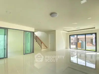 Spacious modern living room with large windows and glossy tiled floors, perfect for natural light and open living.