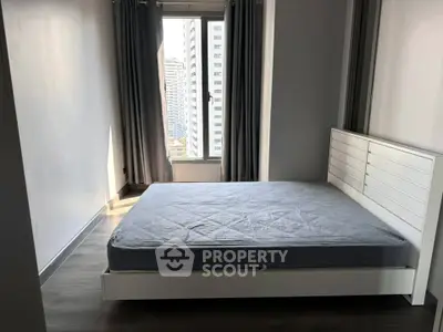 Modern bedroom with large window and city view, featuring a sleek bed frame and minimalist design.