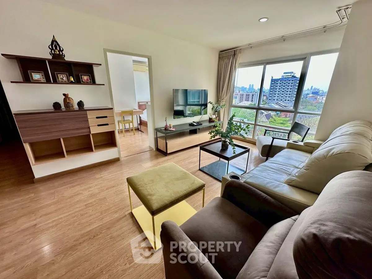 Spacious living room with modern decor and large window offering city views