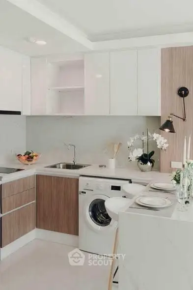Modern kitchen with sleek cabinetry and built-in washing machine, featuring elegant decor and dining setup.