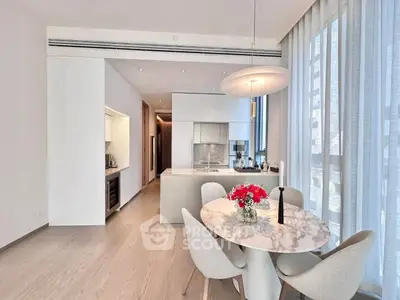 Modern kitchen with open layout and elegant dining area featuring marble table and contemporary lighting.