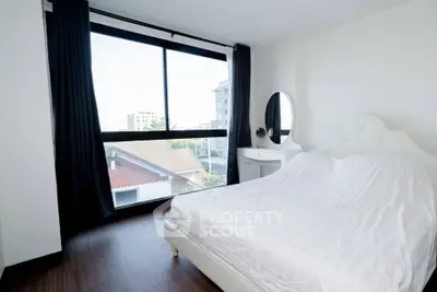 Bright bedroom with large window and modern furnishings in a stylish apartment.