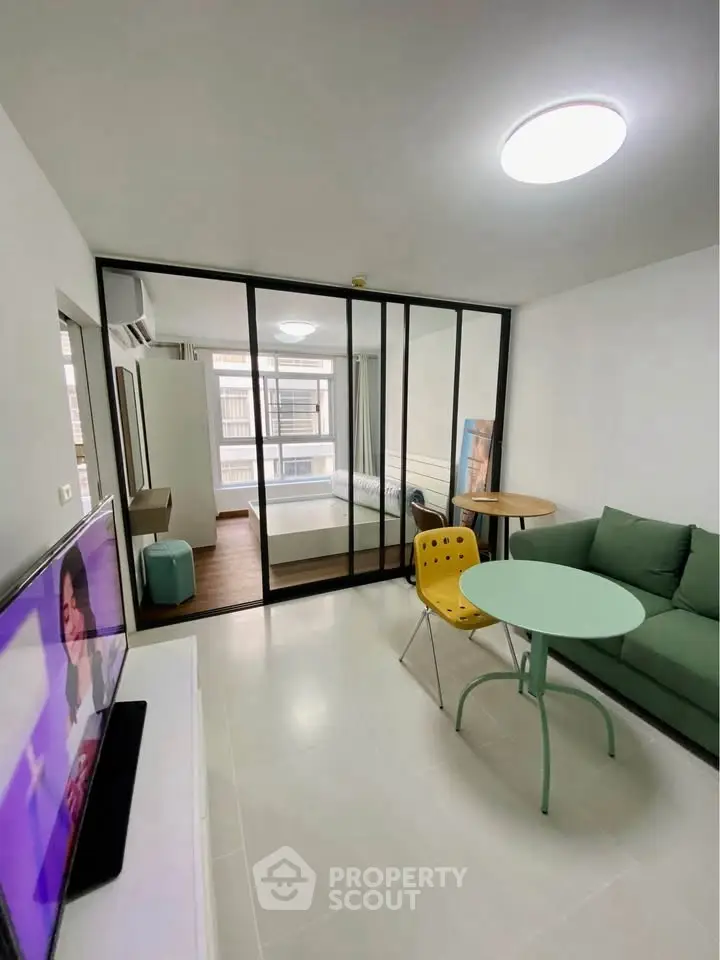 Modern studio apartment with glass partition, cozy living area, and natural light.