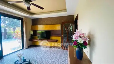 Spacious living room with modern decor and large windows opening to a garden view.