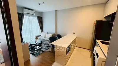 Modern open-layout living room with kitchen, featuring sleek design and natural light.