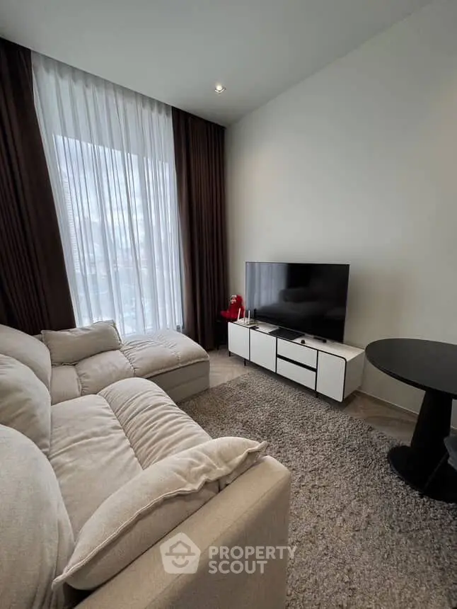 Cozy modern living room with plush sofa and large TV, perfect for relaxation.