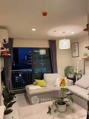 Modern living room with cozy sofa and city view from balcony at night.