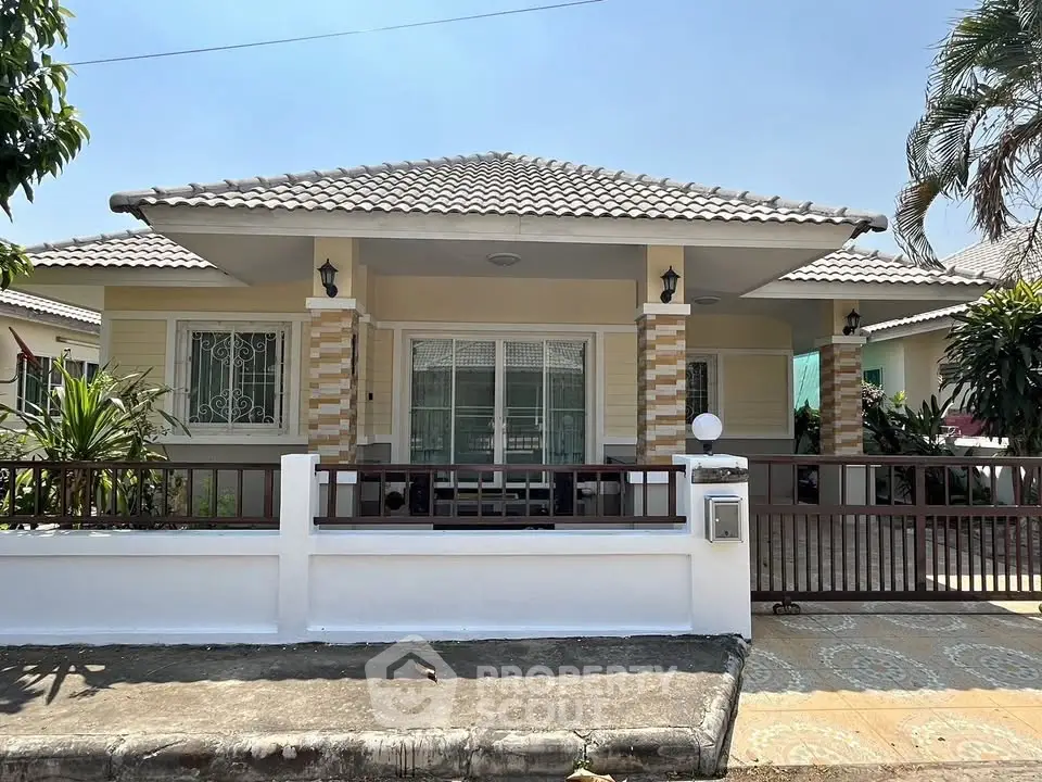 Charming single-story house with tiled roof and gated entrance in a serene neighborhood.