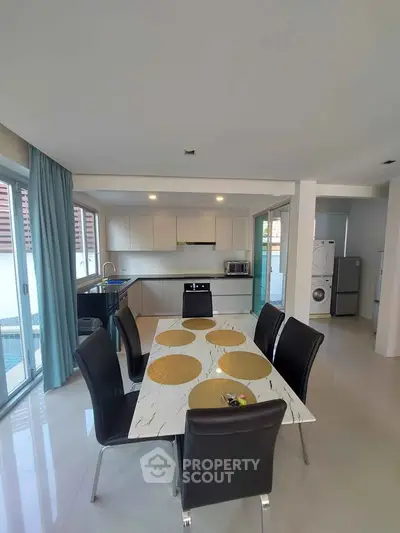 Modern open-layout kitchen and dining area with sleek design and pool view.