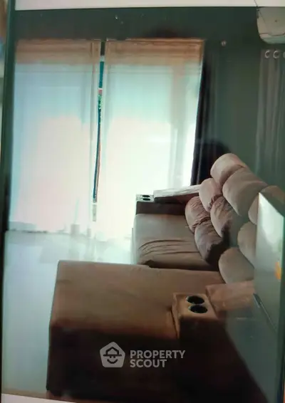 Spacious living room with plush sofa and natural light through large windows.