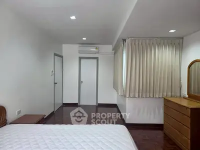 Spacious bedroom with parquet flooring and natural light