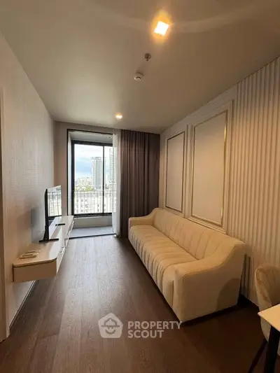 Modern living room with elegant sofa and wall-mounted TV, featuring a city view balcony.