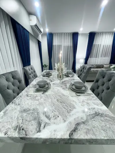 Luxurious dining area with marble table and plush chairs in modern living space.