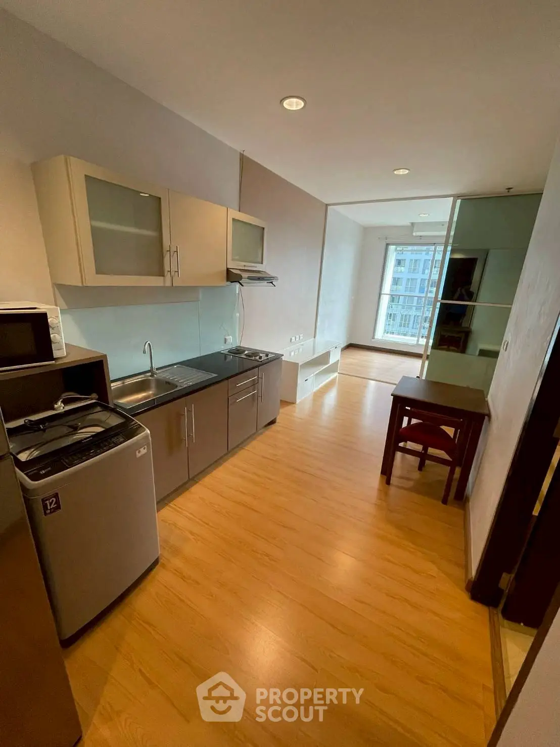 Modern kitchen with sleek cabinetry and wooden flooring in a bright apartment