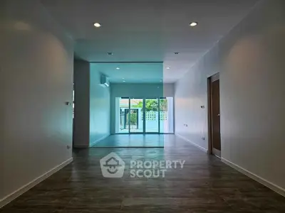 Spacious modern living room with large windows and wooden flooring, perfect for natural light and open living.