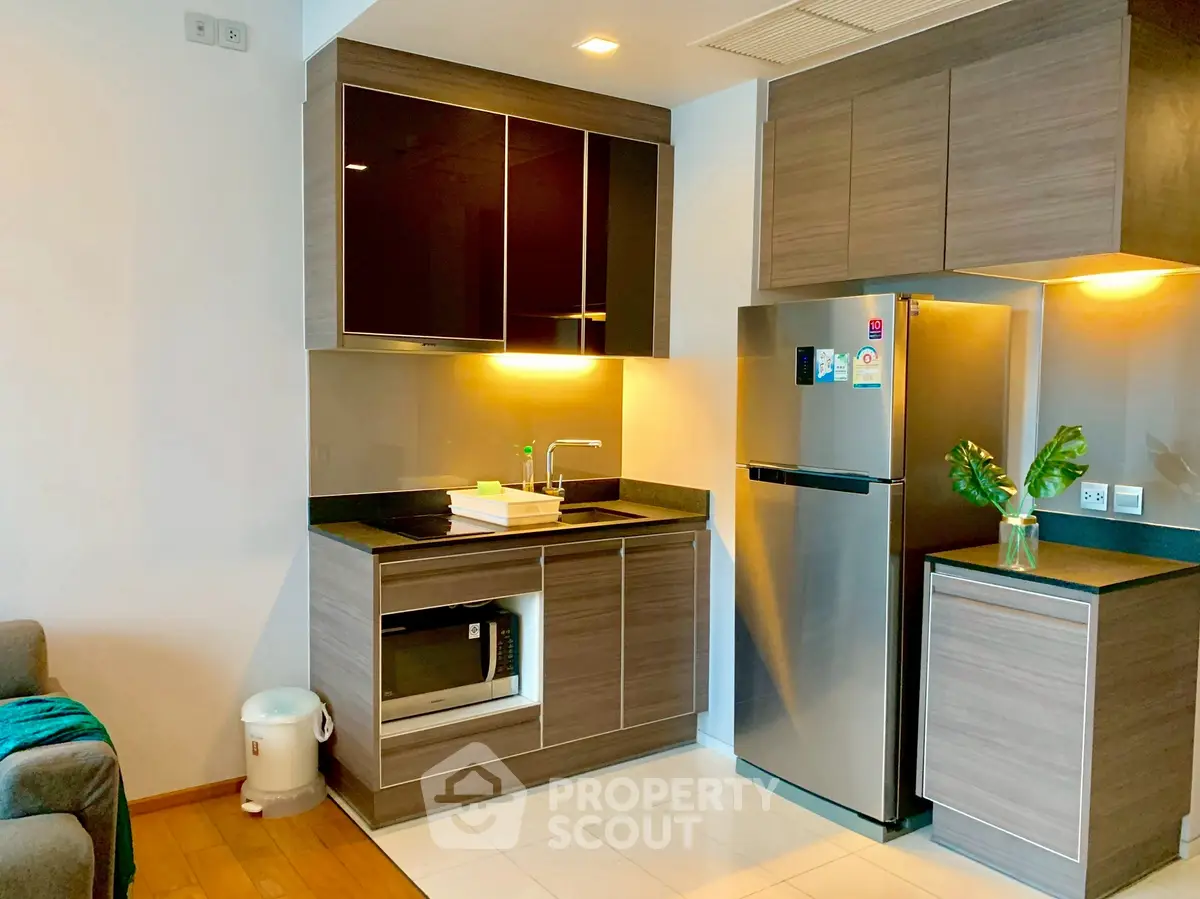 Modern kitchen with sleek cabinetry and stainless steel appliances in a cozy apartment.