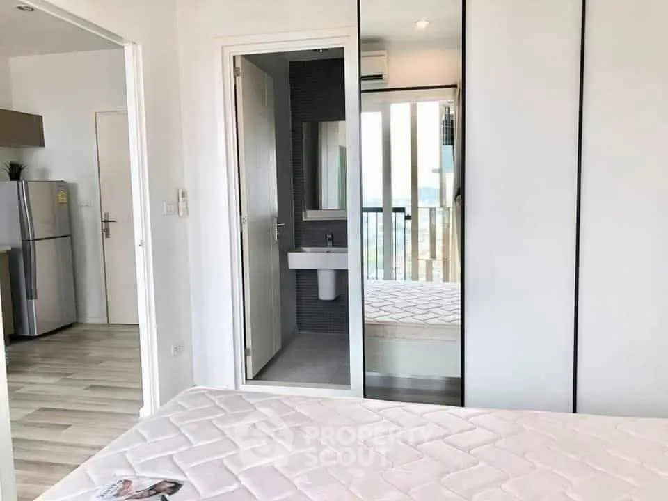 Modern bedroom with mirrored closet and view of sleek kitchen area