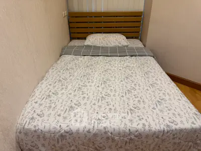 Cozy bedroom with a neatly made bed and wooden headboard, perfect for restful nights.