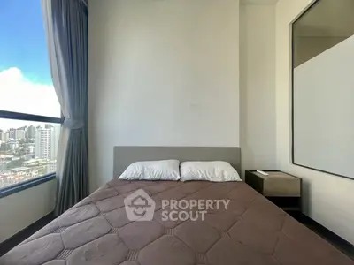 Modern bedroom with city view, featuring a cozy bed and large window for natural light.