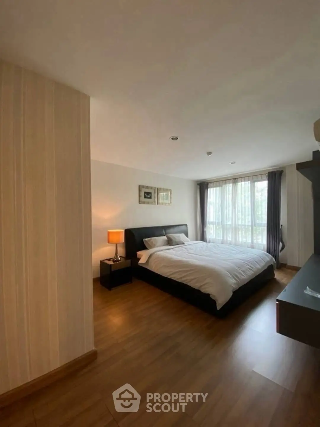 Spacious bedroom with modern decor and large window for natural light.