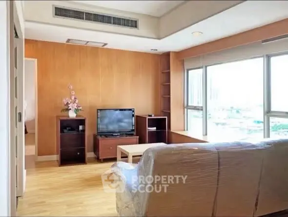 Spacious living room with large windows and modern furnishings in a bright apartment.