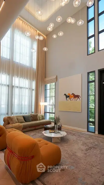 Luxurious living room with high ceilings, modern chandelier, and elegant decor in a spacious home.