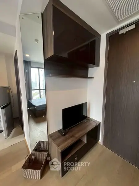 Modern apartment interior with sleek TV stand and mirrored wall accent.