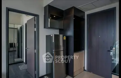 Modern apartment entrance with sleek black cabinetry and stainless steel fridge