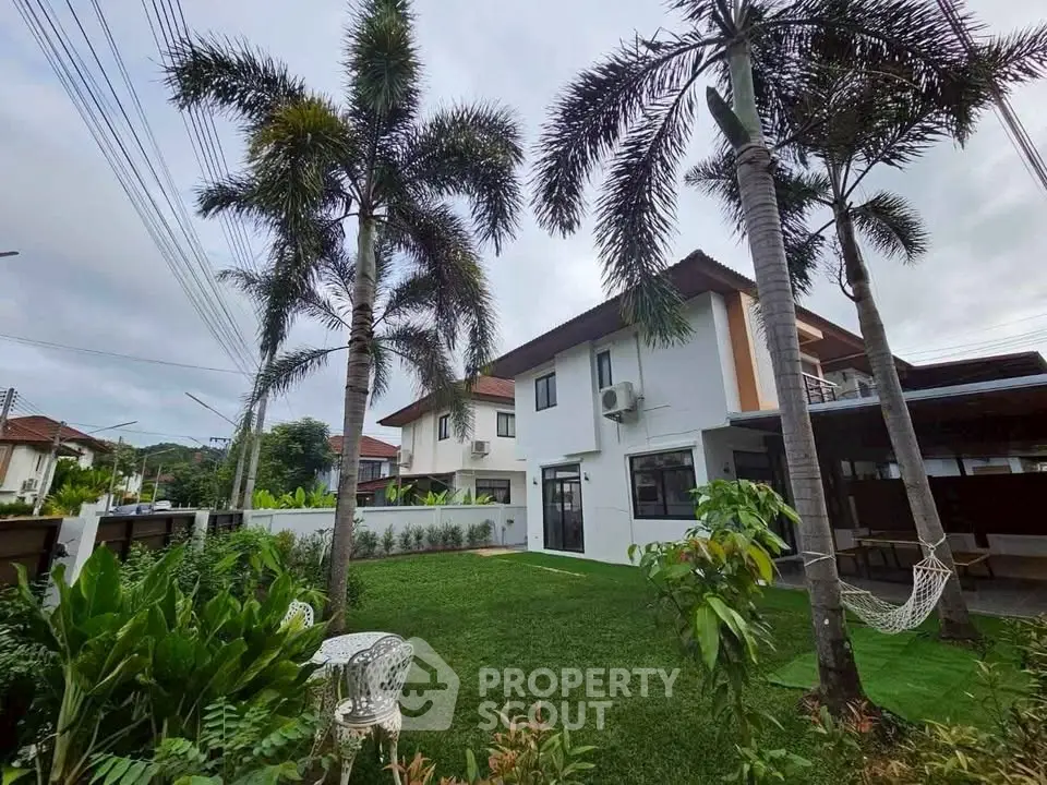 Stunning two-story house with lush garden and palm trees, perfect for serene living.
