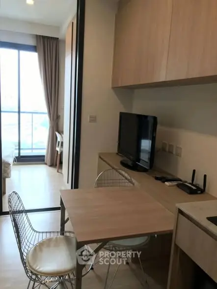 Modern compact living space with TV and dining area, featuring sleek furniture and natural light.